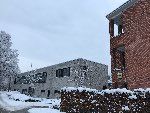 Das Foto zeigt die Stadtteilschule und einen Teil der HCA. im Vordergrund sind Büsche, Bäume und der Vorplatz schneeüberdeckt zu sehen.