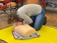 Lehrerin übt an einer Puppe die Mund-zu-Mund-Beatmung